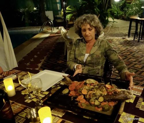 a woman sitting at a table with a tray of food at SAFARI Lodge Location Bungalow in Cap Skirring