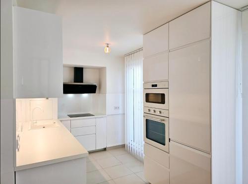 une cuisine blanche avec des armoires et des appareils blancs dans l'établissement The LUXURY in PARIS Terrace Apartment, à Clamart