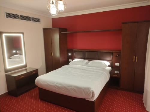 - une chambre avec un grand lit et un mur rouge dans l'établissement Monte Cairo Serviced Apartments, au Caire