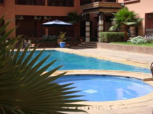 uma piscina com uma palmeira em frente a um edifício em Stylish Art Deco 2/2 - Best Location in Marrakech! em Marrakech