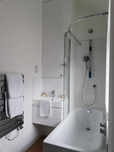 La salle de bains blanche est pourvue d'une baignoire et d'un lavabo. dans l'établissement Kings Road a new development with unique features, à Newbury
