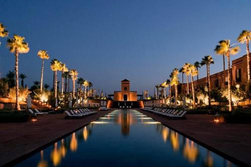 uma piscina de água com palmeiras e um edifício em Stylish Art Deco 2/2 - Best Location in Marrakech! em Marrakech