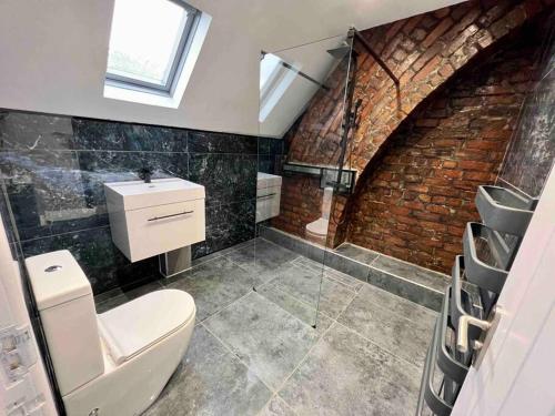a bathroom with a toilet and a sink and a brick wall at Modern City Centre Townhouse sleeps 10 & Parking in Manchester