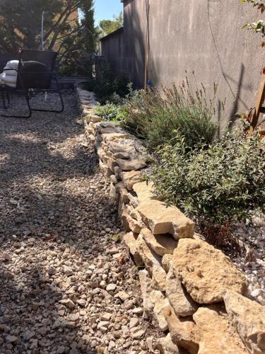 un mur de retenue en pierre dans une cour avec un banc dans l'établissement Lou Atenéncia, à Villes-sur-Auzon