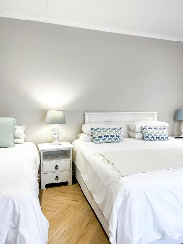 two white beds in a bedroom with a lamp on a night stand at Goulden Street Guest House in East London