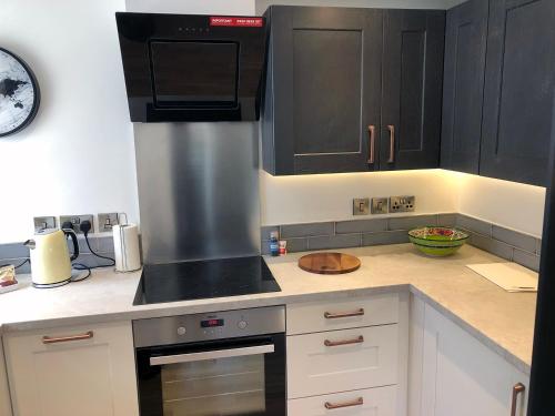 a kitchen with black cabinets and a stove top oven at Crown House is a brand new development with unique features in Newbury