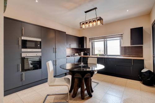 uma cozinha com armários pretos e uma mesa e cadeiras em 10 bedroom Luxurious Villa em East Legon