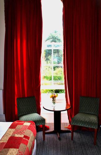 a bedroom with a table and two chairs and a window at Victoria Square Hotel Clifton Village in Bristol