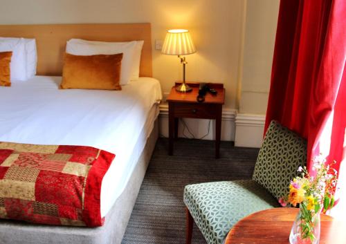 a hotel room with a bed and a chair and a table at Victoria Square Hotel Clifton Village in Bristol