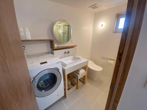 uma casa de banho com uma máquina de lavar roupa e um lavatório em HUB INN 離れ em Habu