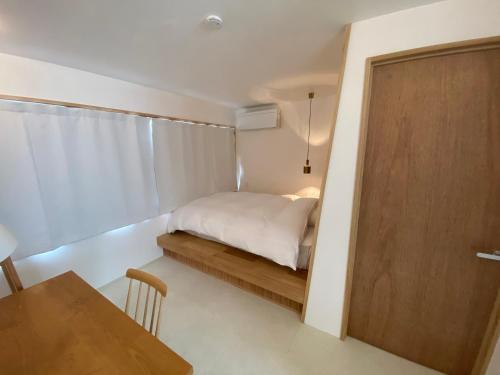 Habitación pequeña con cama y puerta de madera en HUB INN 離れ en Habu