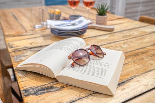 a book with glasses sitting on top of it on a table at Quinta do Ourives in Carvoeiro