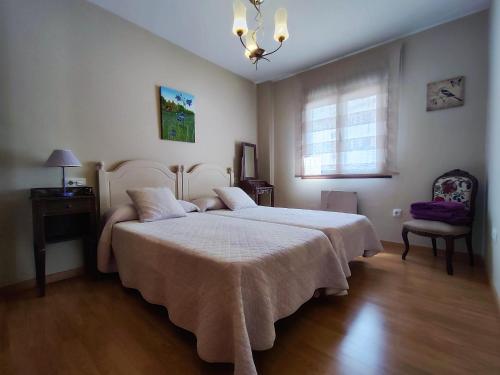 a bedroom with two beds and a chair and a window at Apart. Casa Juaneta Pirineo-Ordesa in Broto