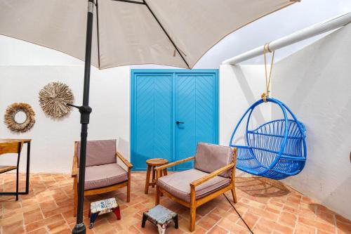 a room with a blue door and chairs and an umbrella at Quinta do Ourives in Carvoeiro