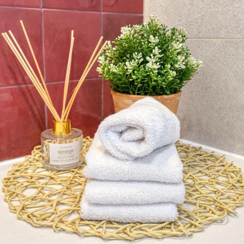 a pile of towels on a wicker tray with a plant at Quinta do Ourives in Carvoeiro