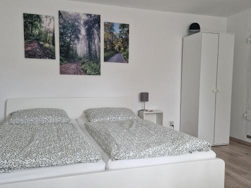 a bedroom with two beds and three paintings on the wall at Waldbergperle Ernsbach in Forchtenberg
