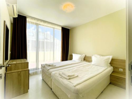 een slaapkamer met een groot bed en een groot raam bij Apartments Stamopolu Lux with pool view in Primorsko