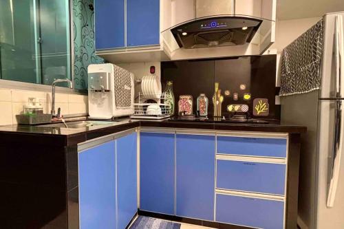 cocina con armarios azules, fregadero y nevera en 'A'ffordable Spacious 6pax S PICE Penang en Bayan Lepas