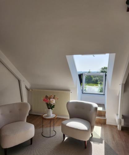 a living room with two chairs and a vase of flowers at Domaine du D-DAY in Saint-Côme-du-Mont