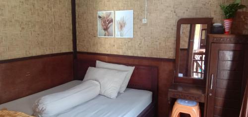 a small bedroom with a bed and a mirror at Radiya Guesthouse in Sembalun Lawang