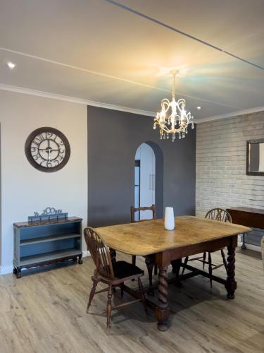 a dining room with a wooden table and a clock at Goulden Street Guest House in East London