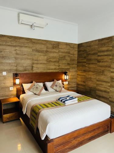 a bedroom with a large bed with wooden walls at Kastapar Bridge Lembongan in Nusa Lembongan