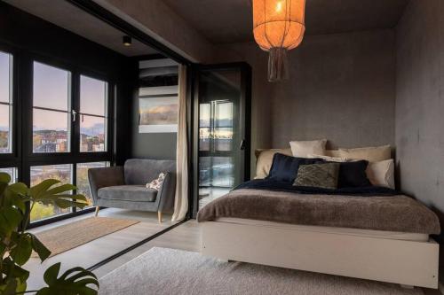 a bedroom with a bed and a chair and windows at Industrial Luxury City Loft in Gothenburg