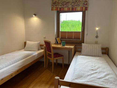 a room with two beds and a desk and a window at Mösslacher's Ferienwohnungen in Hermagor