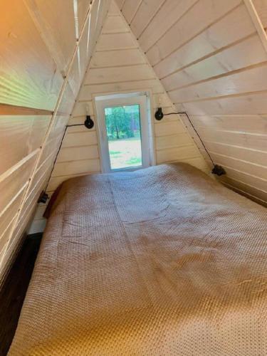 ein großes Bett in einem kleinen Zimmer mit Fenster in der Unterkunft A-frame під Києвом 