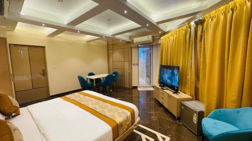 a hotel room with a bed and a tv and chairs at Home2 Renaissance Club in Mumbai