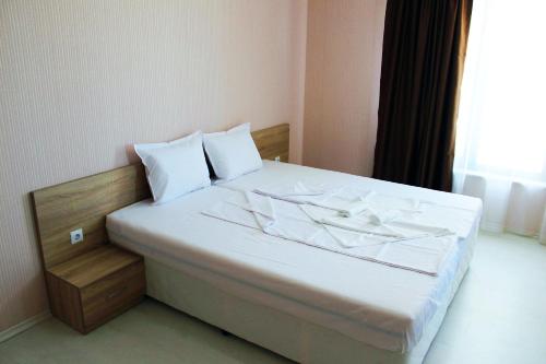 a bedroom with a bed with white sheets and a window at Private apartments Stamopolu lux in Primorsko