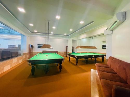 a room with two pool tables and a couch at Home2 Renaissance Club in Mumbai