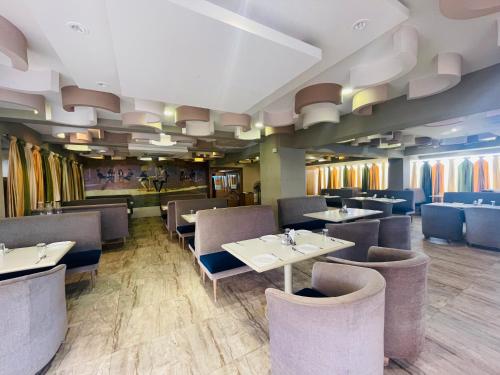 a restaurant with tables and chairs in a room at Home2 Renaissance Club in Mumbai