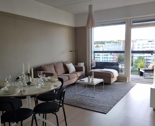 Hotellitasoinen, uusi huoneisto! في تامبير: غرفة معيشة مع أريكة وطاولة وكراسي