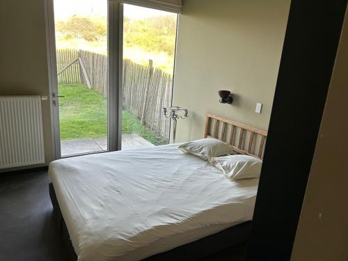 a bed in a bedroom with a large window at Apartment Ostend Dune in Ostend