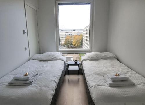 2 Einzelbetten in einem Zimmer mit Fenster in der Unterkunft Hotellitasoinen, uusi huoneisto! in Tampere