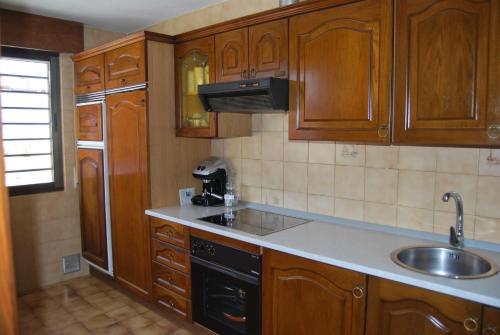 a kitchen with wooden cabinets and a sink at Casa rural Puente Mocho in Ledesma