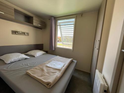 a small bedroom with a bed and a window at Mobilehome lumineux 2 chambres - 4 personnes - Proche Europa Park in Boofzheim