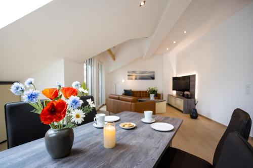 a living room with a wooden table with a vase of flowers at Villa Beatrice - WE 13 mit eigener Sauna, 2 Dachterrassen, kleiner Meerblick in Binz