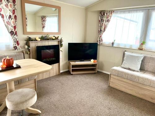 a living room with a television and a couch and a table at 6 Birth Caravan Ingoldmels in Ingoldmells