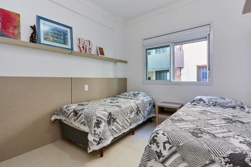 ein Schlafzimmer mit zwei Betten und einem Fenster in der Unterkunft 1054 - Apartamento Centro de Bombinhas - Vista Mar - 1 Vaga Garagem - 50 metros Praia in Bombinhas