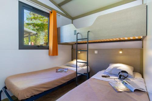 グレウー・レ・バンにあるCamping Paradis La Pinedeのベッドルーム1室(二段ベッド2台、窓付)が備わります。