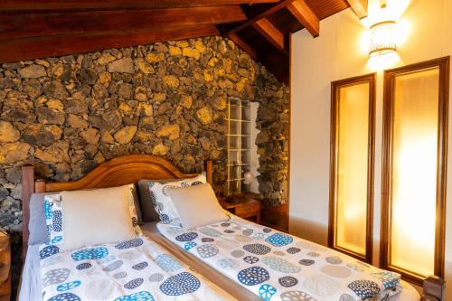 un lit dans une chambre avec un mur en pierre dans l'établissement CASA RURAL LA PERLA NEGRA, à Icod de los Vinos