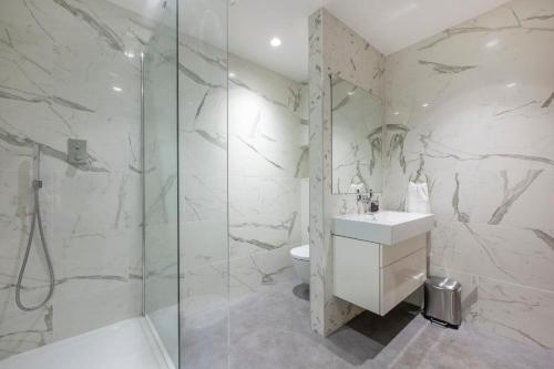 uma casa de banho branca com um chuveiro e um lavatório. em *RE7C* Ground floor room, For your most relaxed & Cosy stay + Free Parking + Free Fast WiFi * em Batley