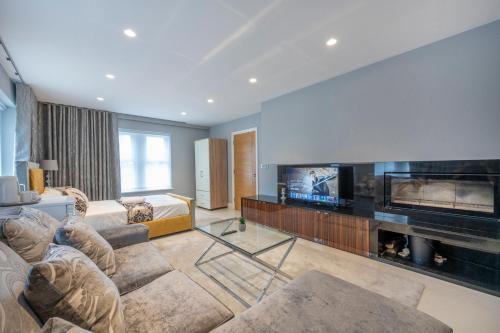 uma sala de estar com uma televisão, um sofá e uma lareira em *RE7C* Ground floor room, For your most relaxed & Cosy stay + Free Parking + Free Fast WiFi * em Batley
