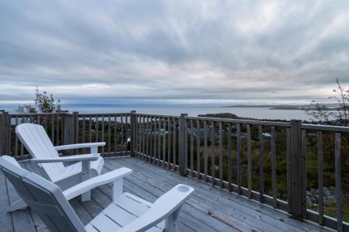 two chairs on a deck with a view of the ocean at Belle Vue Cottage - Upper Island Cove in Upper Island Cove