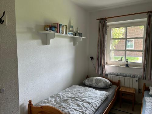 Habitación pequeña con cama y ventana en Ferienwohnung Moby Dick, en Ording