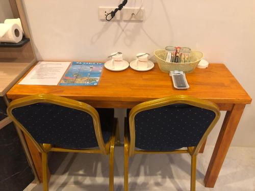 a wooden table with two chairs and a table with a book at M&N Guesthouse Kata in Kata Beach
