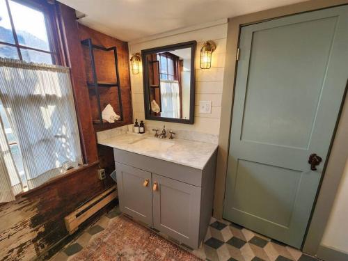 ロックポートにあるThe Orca Suite- Bearskin Neck Rockport- Steps to allの洗面台と鏡とドアのあるバスルーム