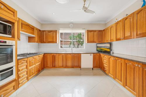 a large kitchen with wooden cabinets and a window at Gardens of Eden Sydney North in Sydney